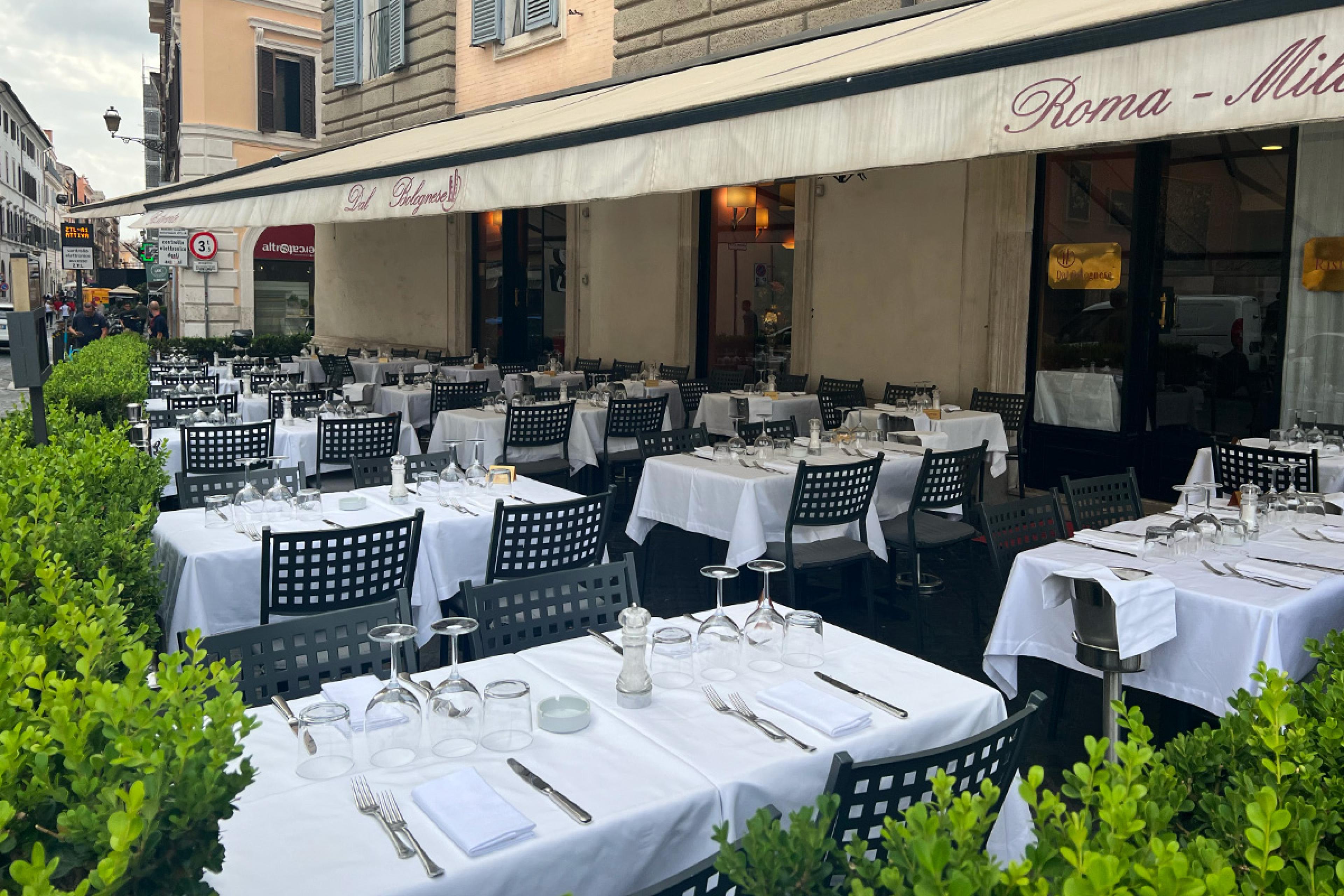 tables with white tablecloths beneath a beige awning