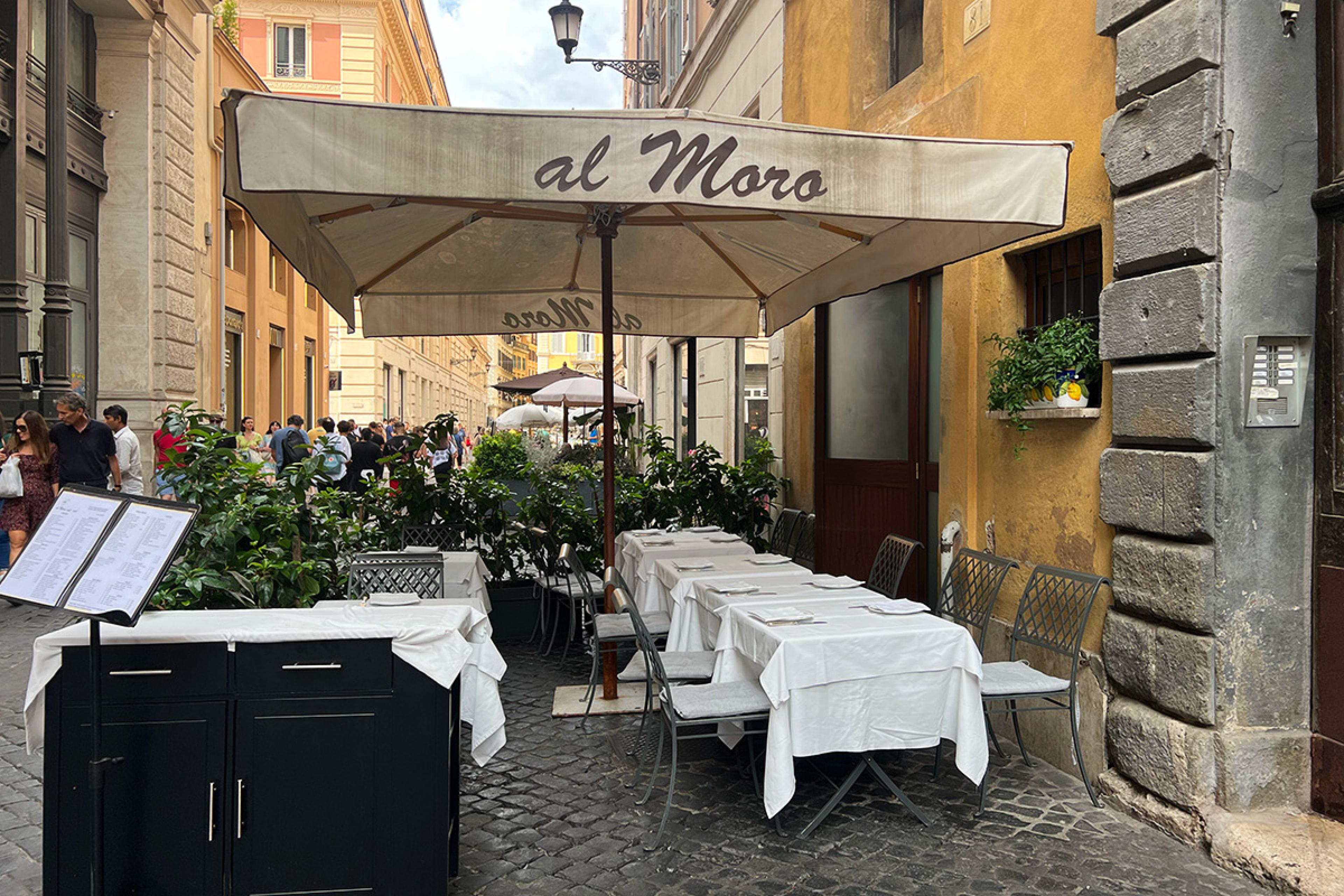 tables with white tablecloths on a cobblestoned street