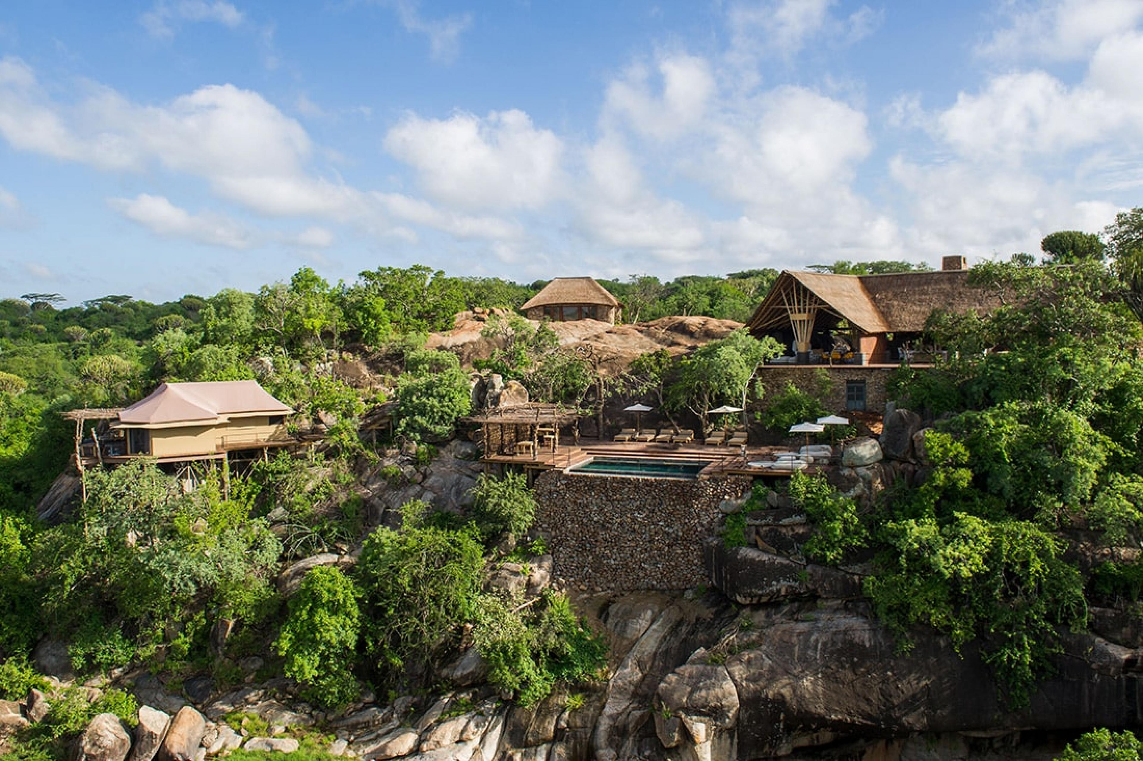 view of Mwiba Lodge from above, with lodge appearing on ledge surrounded by trees