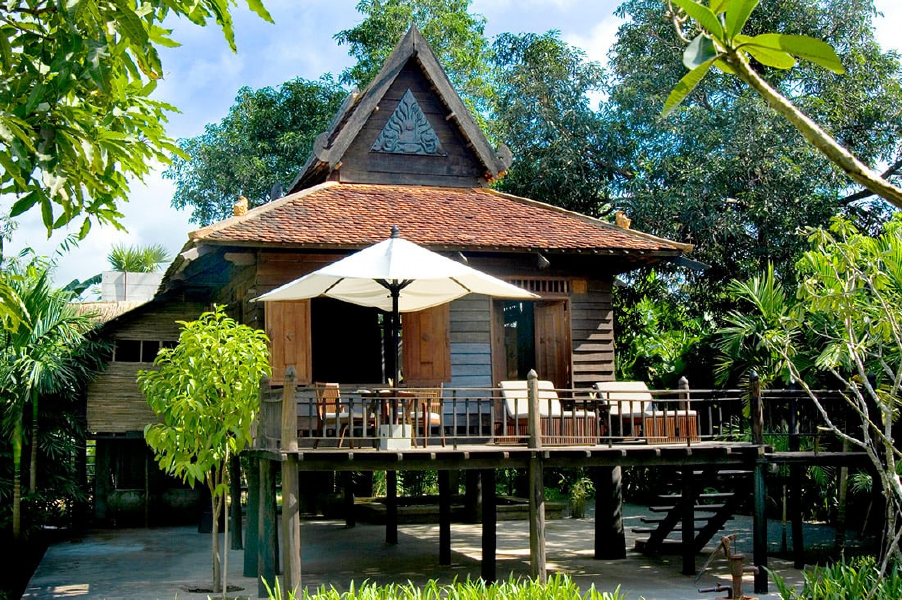 khmer style house with pointed roof and wooden terrace in daytime