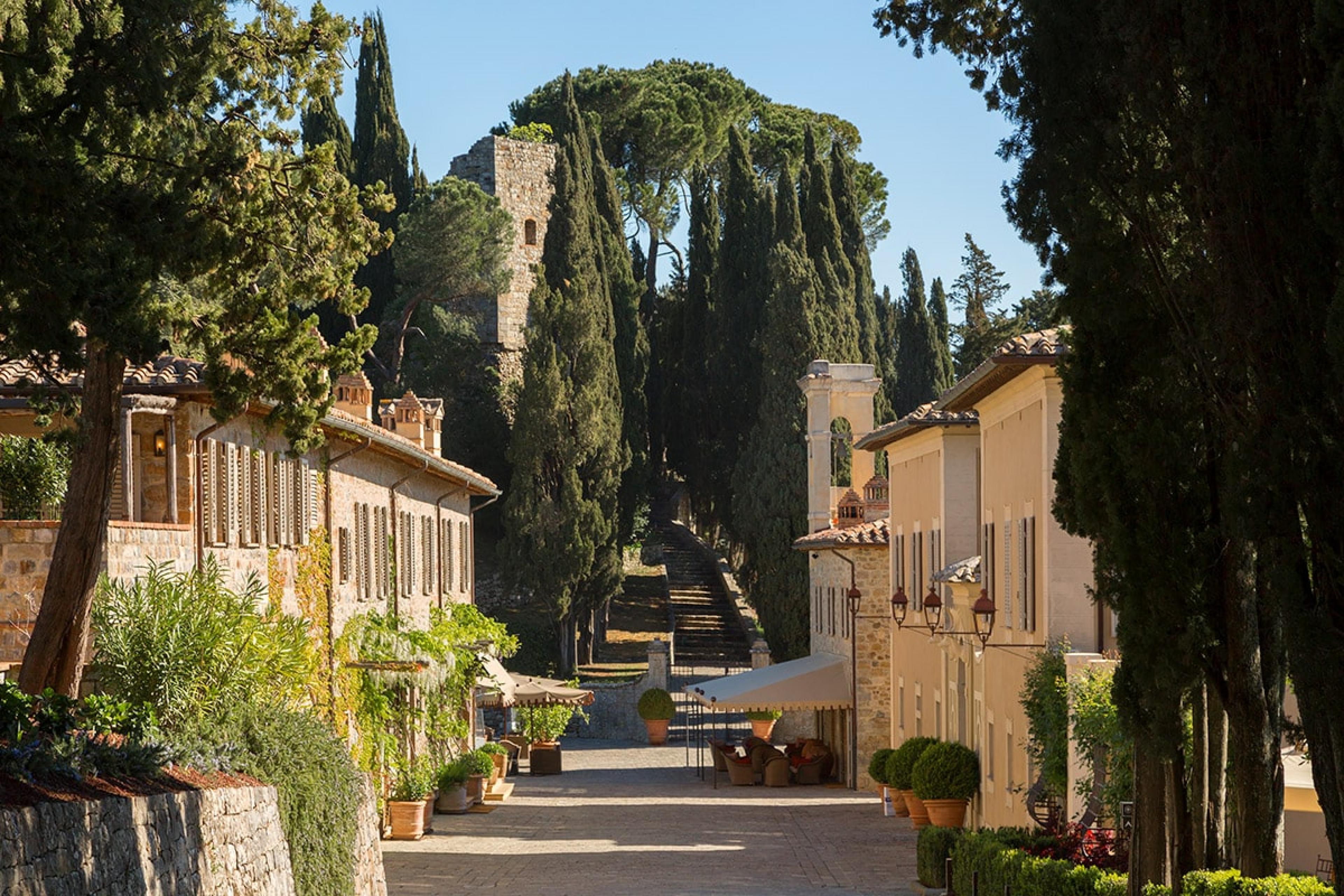 a road leading though historic italian town towards castle ruins behind 